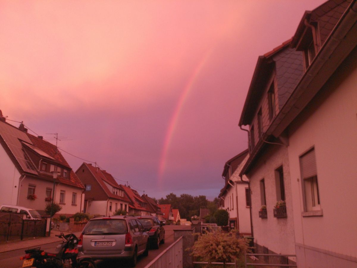 Episches Himmel rot durchdrungen von einem Regenbogen.